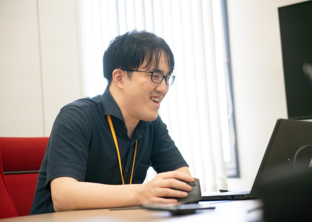 写真 株式会社いい生活の合田様 笑顔でノートパソコンを見つめながら話している